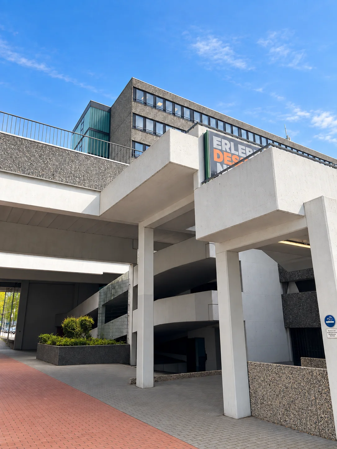 Skulpturale Betonstege und Stützen unter dem Studiogebäude vor blauem Himmel